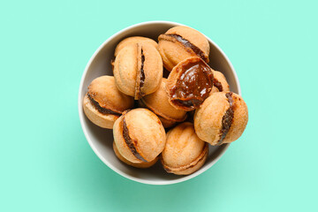Bowl of sweet walnut shaped cookies with boiled condensed milk on turquoise background