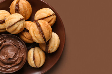 Bowl of sweet walnut shaped cookies with boiled condensed milk on brown background