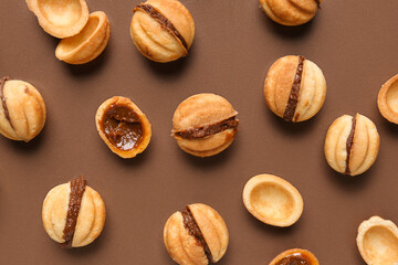 Many sweet walnut shaped cookies with boiled condensed milk on brown background