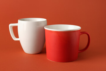 Different ceramic cups on orange background