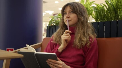 Woman sits in a coffee shop, writing in a notebook. Deep in thought, she focuses on her work, reflecting on ideas and planning her goals while enjoying her beverage