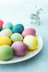 Multi-colored Easter eggs in an oval dish with decorative bunnies on a blue background, Happy Easter holiday