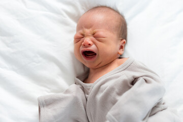 Asian new born babe crying and lying on bed