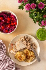 A healthy meal of green buckwheat with chicken breast, zucchini pancakes, fermented vegetable salads and celery cucumber smoothie