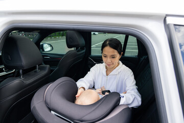 Mother securing baby in car seat safely