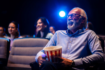 Older man enjoying retirement in the cinema by watching a movie.