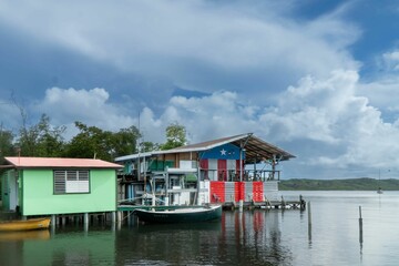 Fototapeta premium Colorful houses on stilts over water with boats docked in a tranquil bay in Puerto Rico