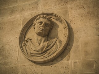 Ancient stone relief sculpture of a Roman figure on a textured wall in Andalusia, Spain