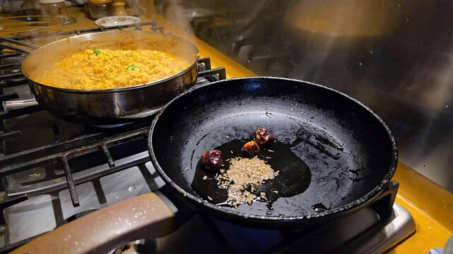 Pouring cumin or zeera in a frying pan for cooking mash daal. 