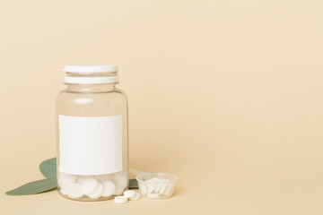 Bottles with pills and green leaves on color background