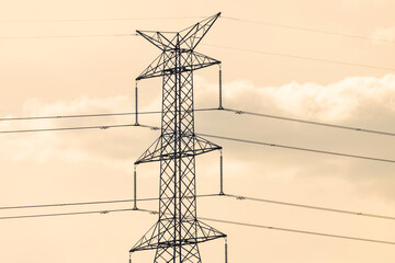 Photograph of the top section of an electricity Transmission Tower against an orange sunset sky in...