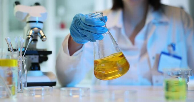 Chemist holding test flask with chemical liquid and fuel for cleaning