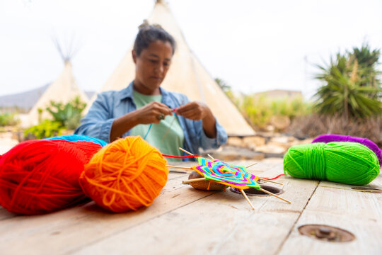 Woman Crafting Outdoors with Colorful Yarn Amidst Teepees