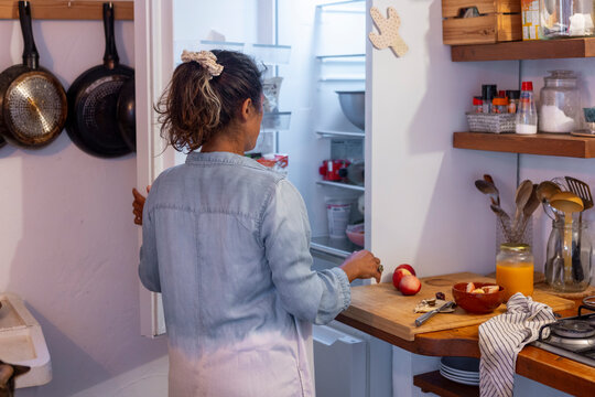 Woman in cozy kitchen preparing meal with fresh ingredients