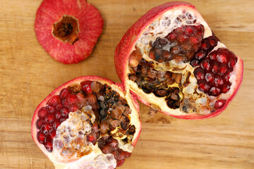 Halved moldy pomegranate on a wooden cutting board, mold on fruit can be harmful to health