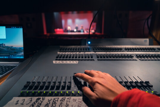 Theater Lighting Control Desk in Action with Hand Adjusting