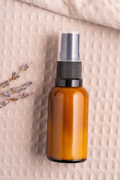 Brown glass spray bottle with flowers on textured fabric