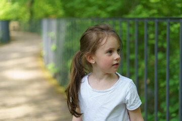 Beautiful cheerful girl in a white T-shirt having fun in the summer outdoors. Concept of an active, mobile, sincere child © PeterPike