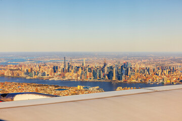 Obraz premium Aerial view of Manhattan skyline with Hudson River and iconic skyscrapers during golden hour from airplane window in flight. USA.