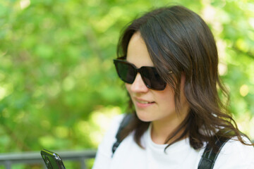 Beautiful smiling dark-haired girl in a white T-shirt and with a backpack on her shoulders in the summer on a trip. Pedestrian wanderung concept