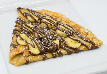 Panqueques con plátano y chocolate en un plato blanco