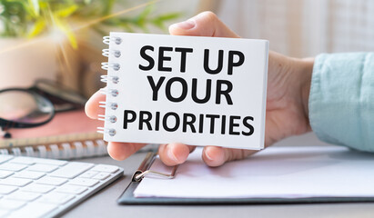 Set Up Your Priorities Text on an Open Notebook in Hand, Calculator, Business Concept