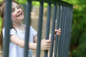 Beautiful cheerful girl in a white T-shirt having fun in the summer outdoors. Concept of an active, mobile, sincere child