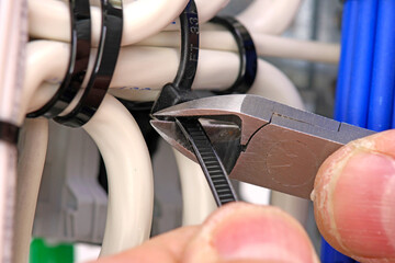 Obraz premium Cutting plastic ties on insulated wires with a tool.