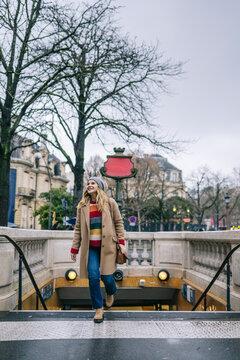 Woman Exiting Paris Metro on Cloudy Day
