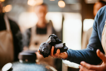 person holding charcoal, focus on pieces, soft background blur