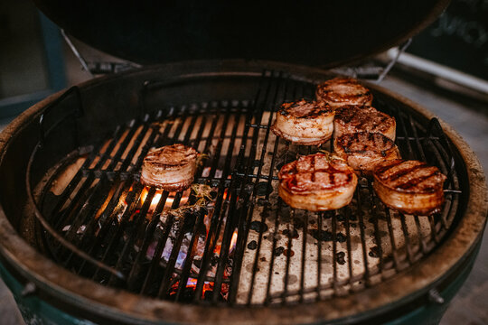 perfectly grilled bacon-wrapped filet mignons on charcoaled grill.