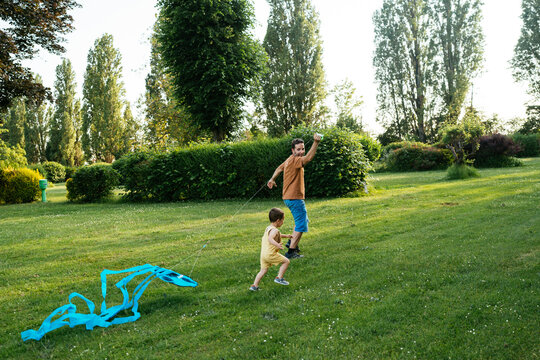 Happy dad and son running on lawn while launching kite