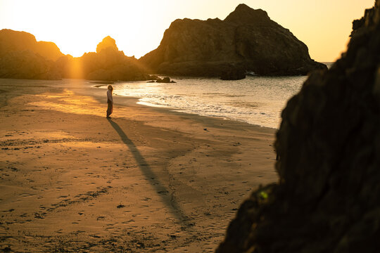 woman standing at sunset in front of the ocean