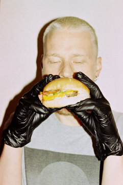 A person with short hair enjoys a burger