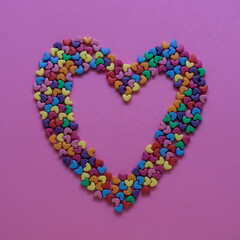 small multi colored hearts forming a big heart on pink background