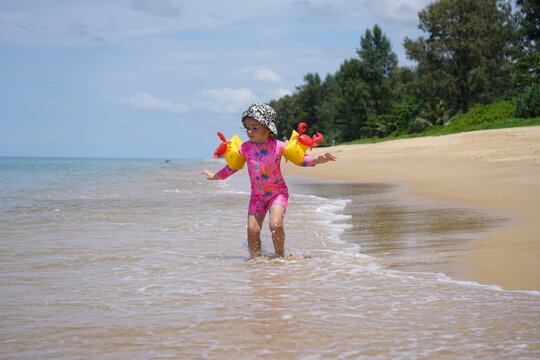 cute child enjoys coconat milk sitting onbeach sand