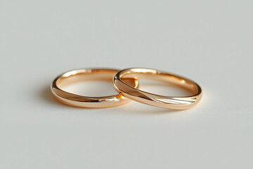 Two Gleaming Gold Wedding Bands Resting on a White Surface, Symbolising Love and Commitment