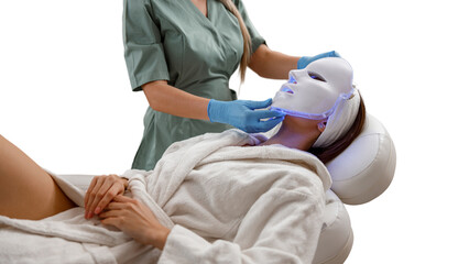 A woman undergoing photon therapy with an LED face mask for cosmetic procedures. Transparent...