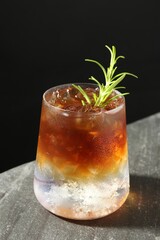 Refreshing espresso tonic drink with rosemary on dark table