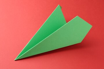 One handmade green paper plane on red background