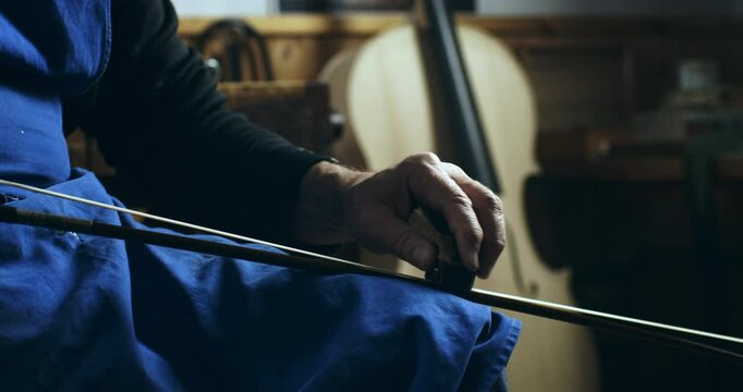 Super slow motion close up of experienced master luthiers hands polish violin bow with precision and care at 1000 fps. Each precise movement highlights artistry and expertise behind creation.