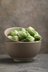 Fresh Brussels sprouts in bowl on grey table