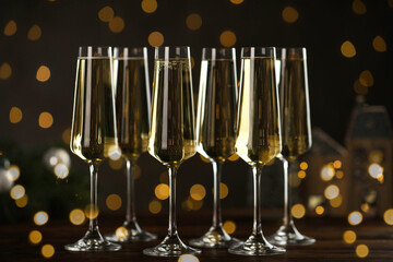 Champagne in glasses and decor on wooden table against blurred Christmas lights. Bokeh effect