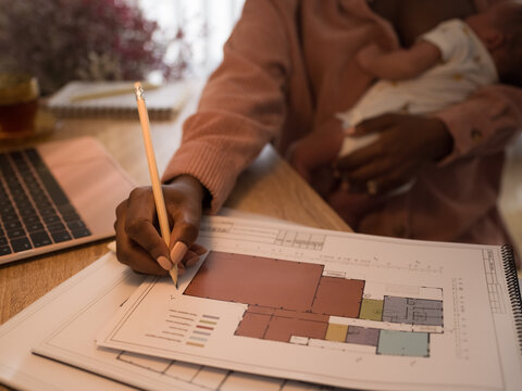 Architect making marks on blueprint while breastfeeding