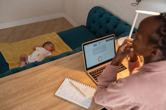 Woman watching her newborn sleeping while working