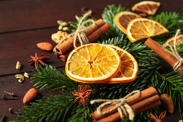 Different spices, dried orange slices and fir tree branches on wooden table, closeup. Christmas...