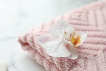 Orchid flower and towel on white marble table, closeup