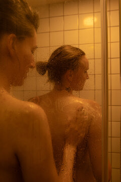 A woman washes another woman's back in the shower