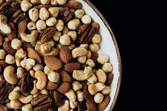 Delicious assortment of mixed nuts in a bowl on dark background