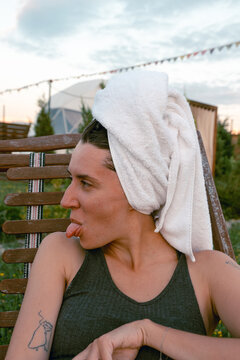 Young woman with towel on head making a funny face outdoors at sunset